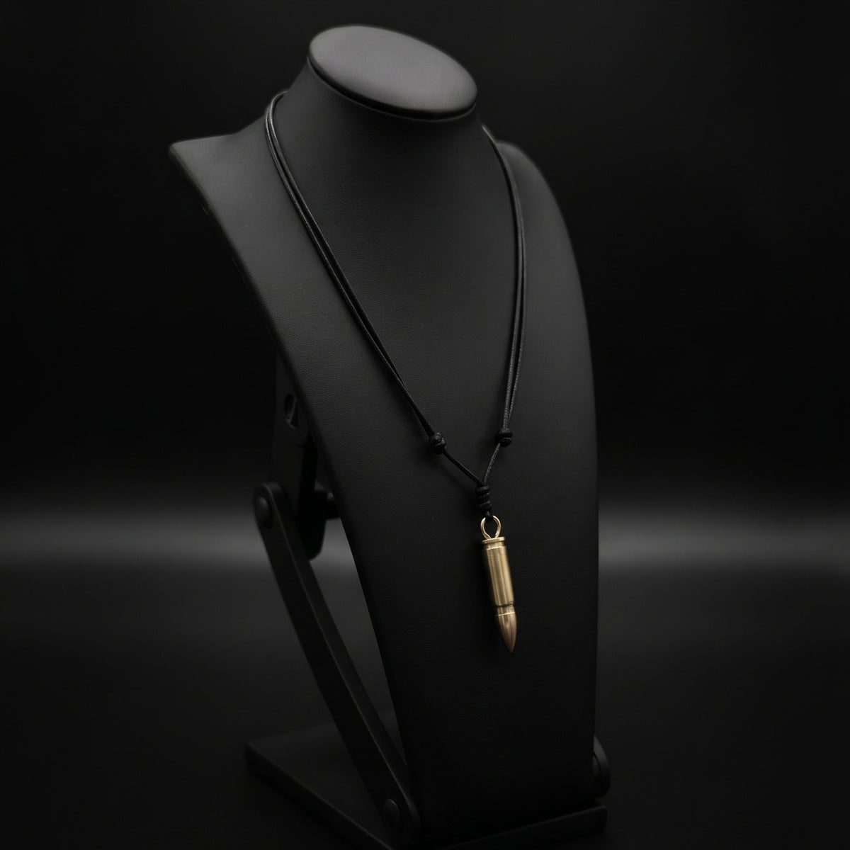 Bullet mini knife necklace by Pocket & Bear Collective on a black display bust, the brass bullet pendant closed on its adjustable black cord