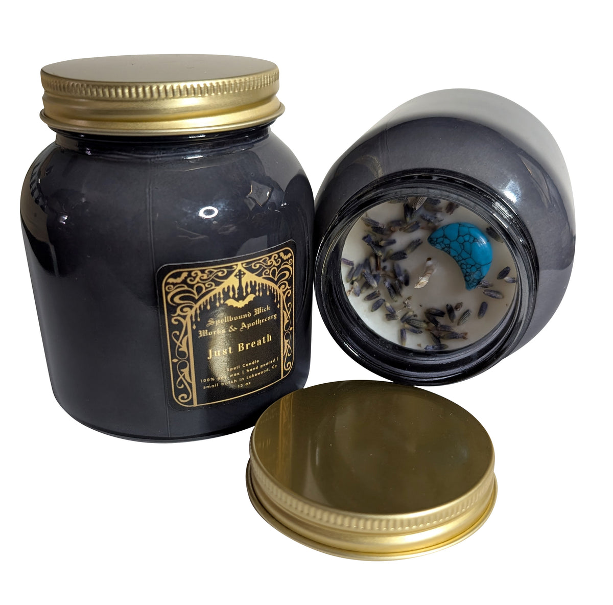 Just Breath spell candle jar tilted to show the white wax top with dried lavender and a blue stone, gold lid resting beside it