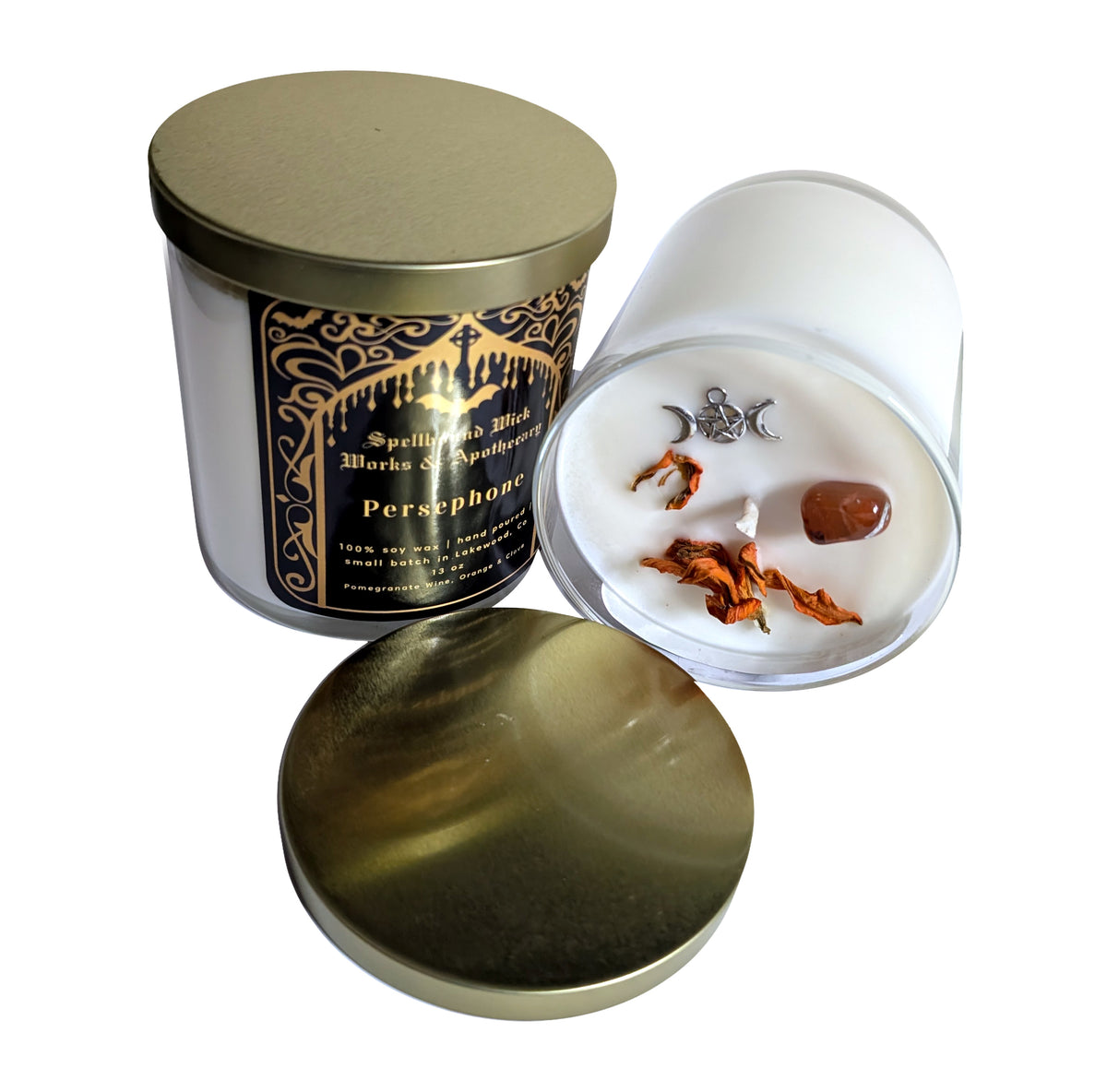 The Persephone Goddess Candle seen from above with the lid removed, next to a white dish of dried botanicals and a brown stone