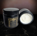 Black jar of body butter with a black lid, shown open beside the closed jar, the whipped white butter smooth across the top.