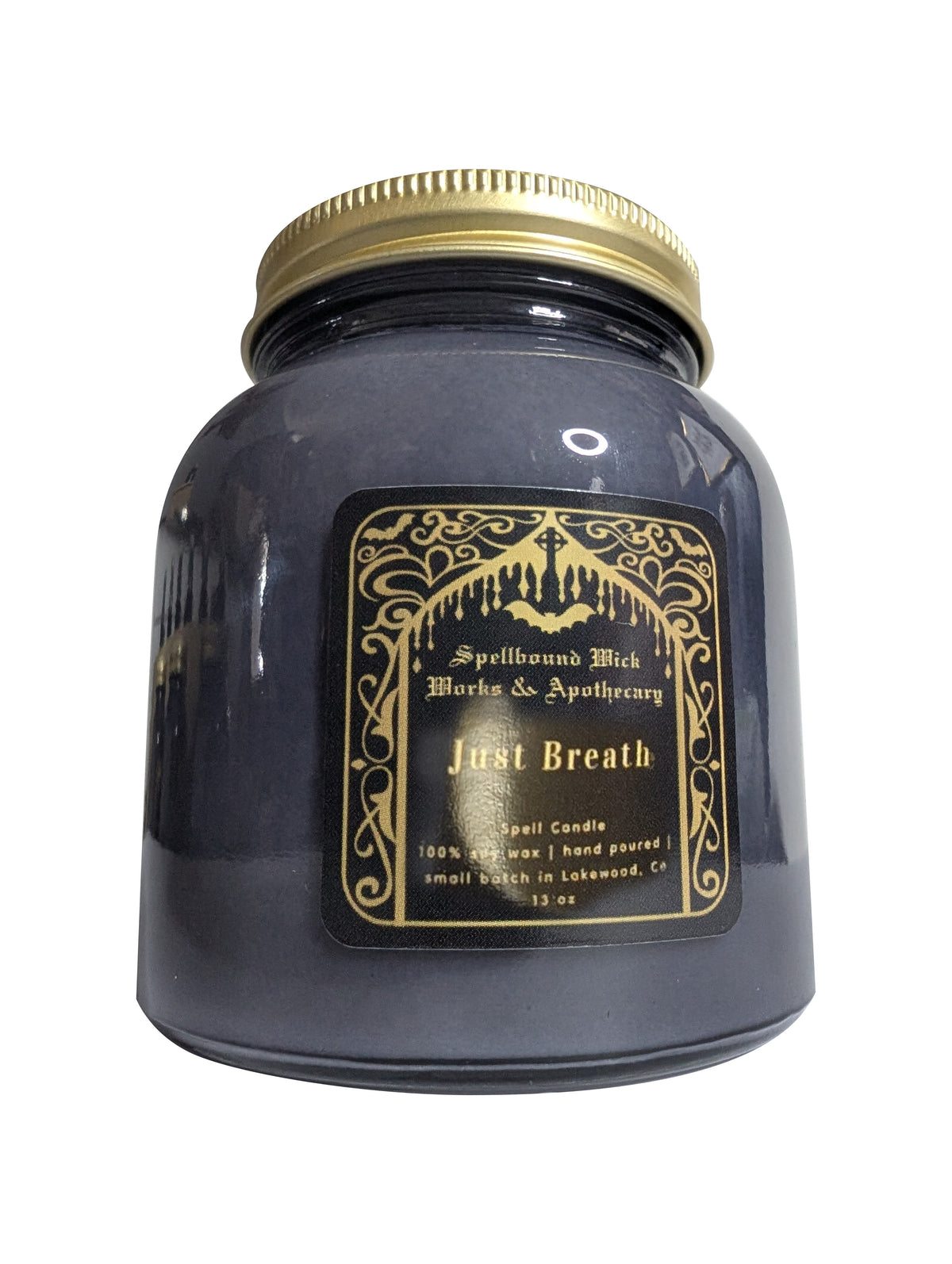 Dark gray Just Breath spell candle in a glass jar with a gold lid and black and gold label, front view on a white background