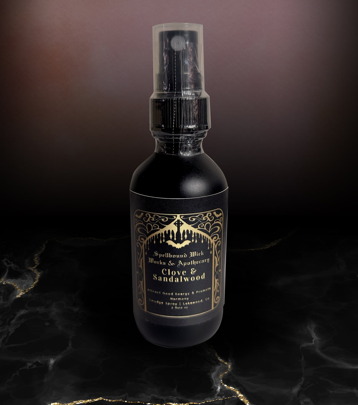 Matte black spray bottle photographed at an angle on marble, the gold label catching the light.