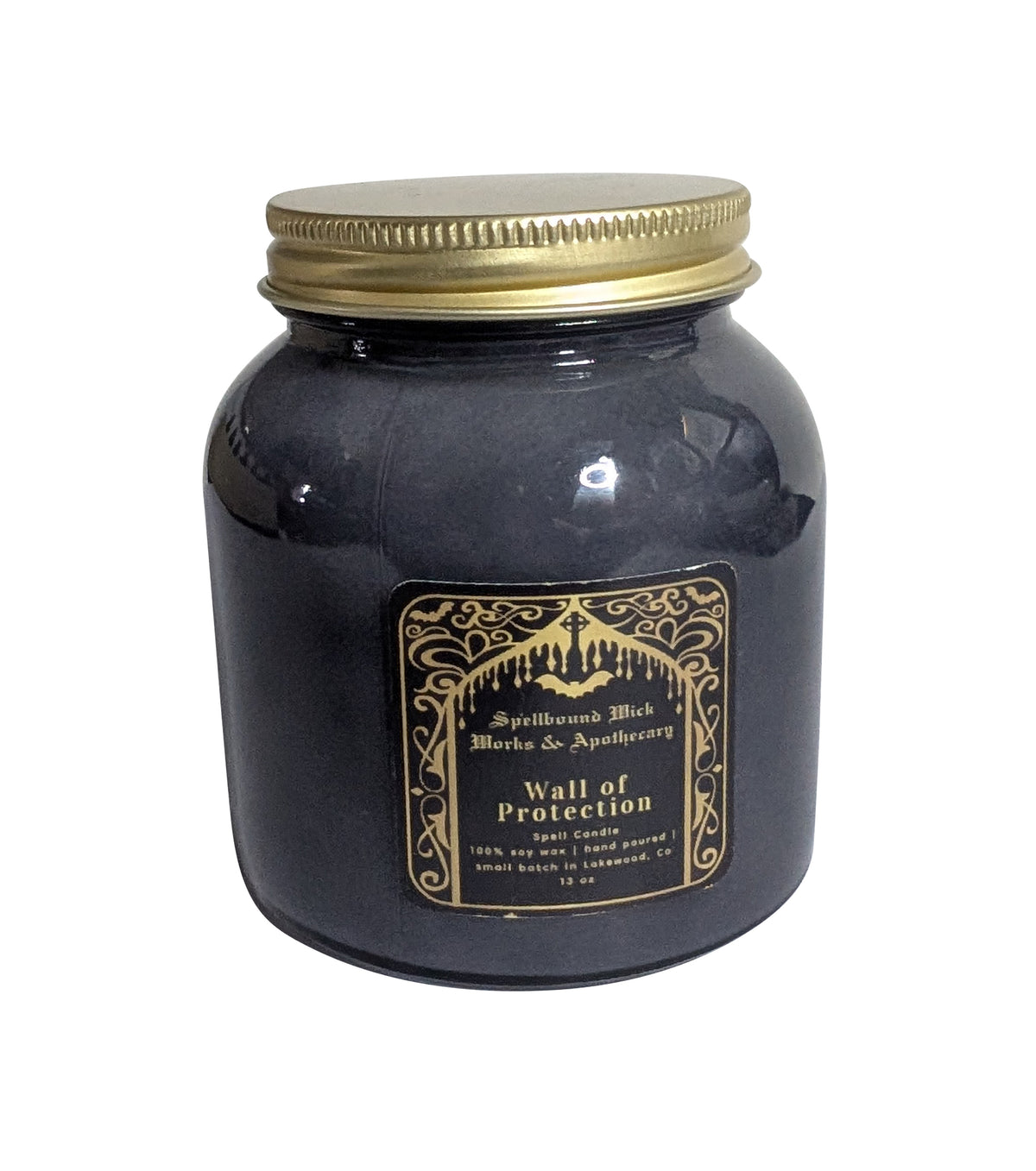 Front view of the closed black jar candle, gold lid screwed on, gold foil label with ornate border.