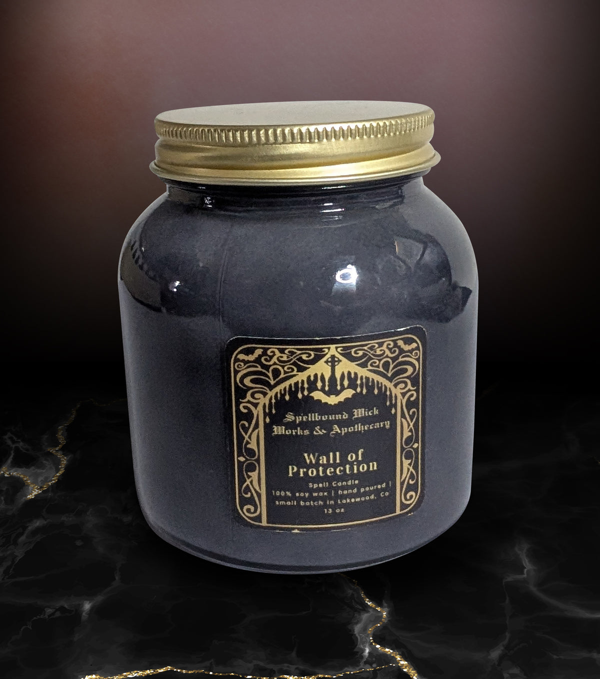 Closed black jar candle with a gold lid, the gold arched label reading Wall of Protection centered on the front.