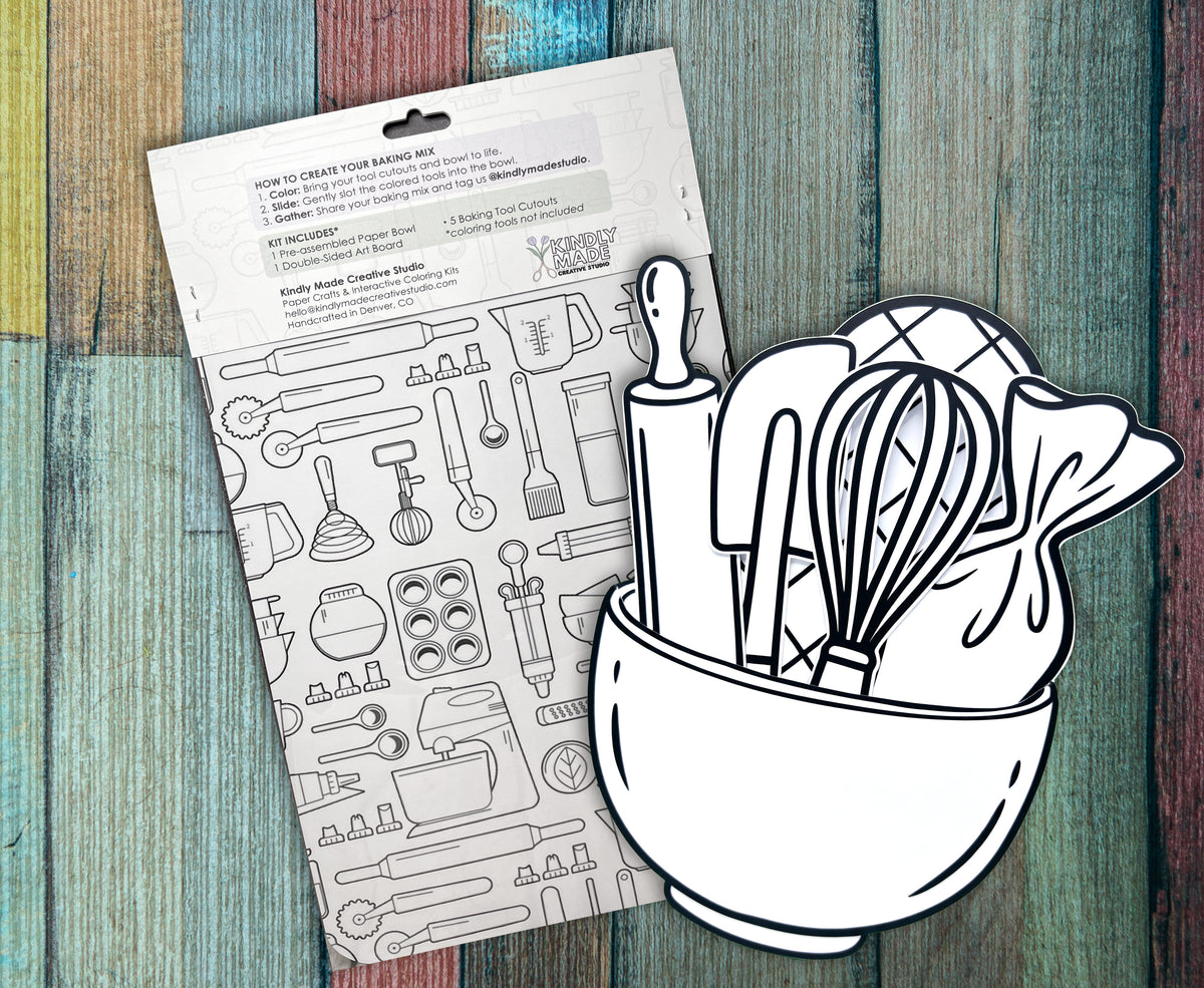 Back of the Baking Mix kit on painted wood, showing the how to instructions and the double sided art board covered in baking tool line drawings, with the assembled bowl and utensil cutouts standing in front.