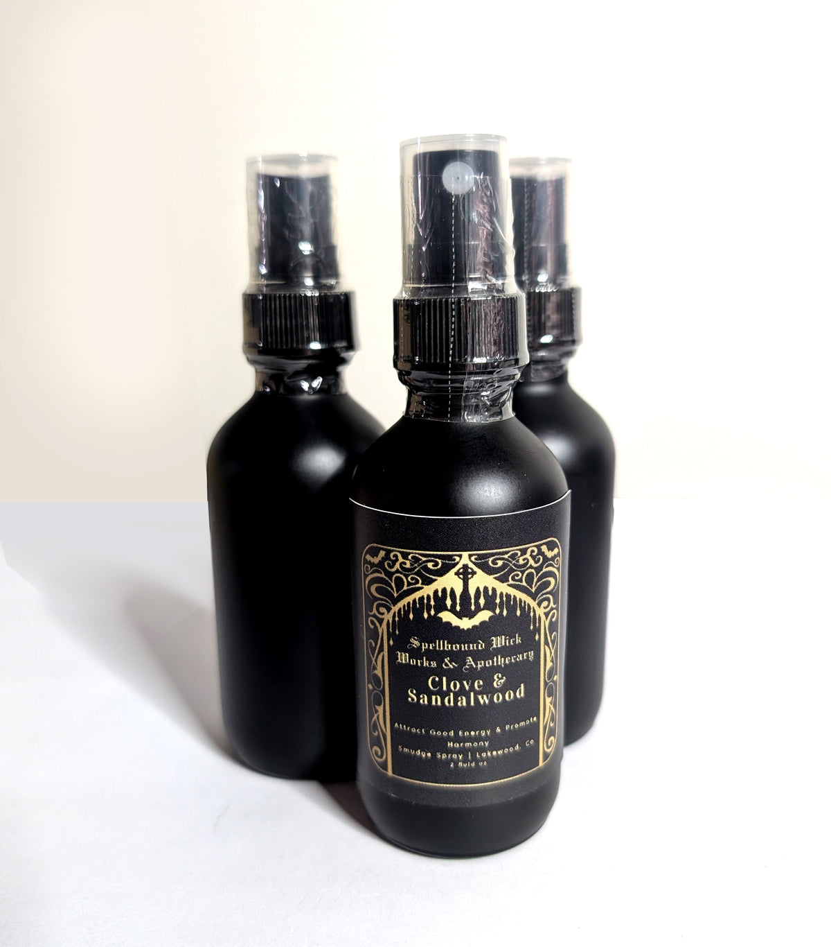 Three matte black spray bottles clustered at an angle on a white background, labels facing the camera.