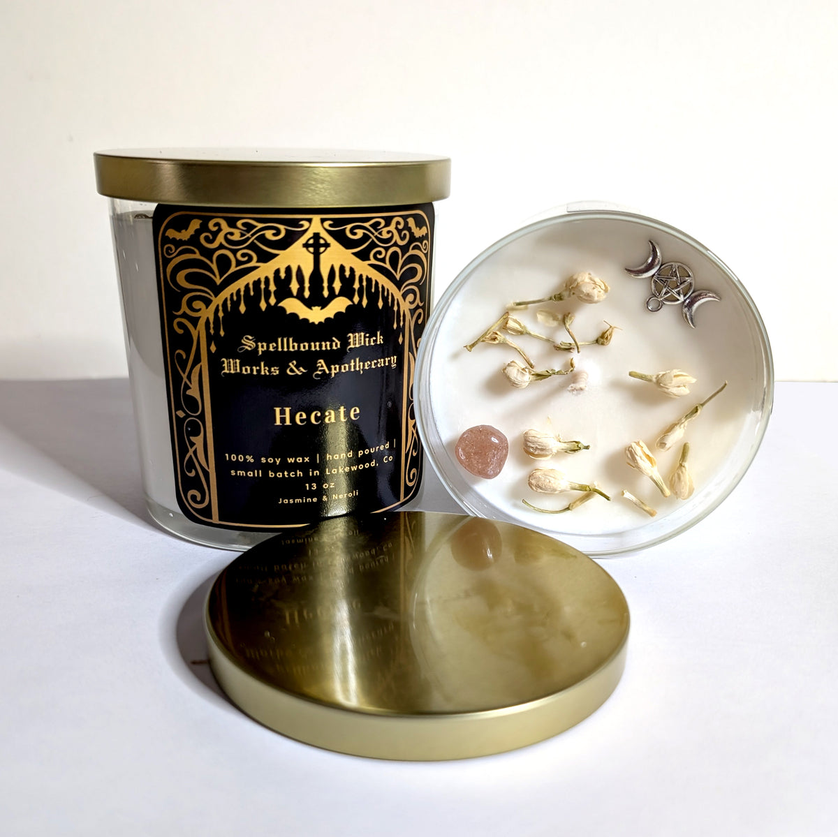 The Hecate Goddess Candle with its gold lid propped against the jar, bone charms in a white dish alongside