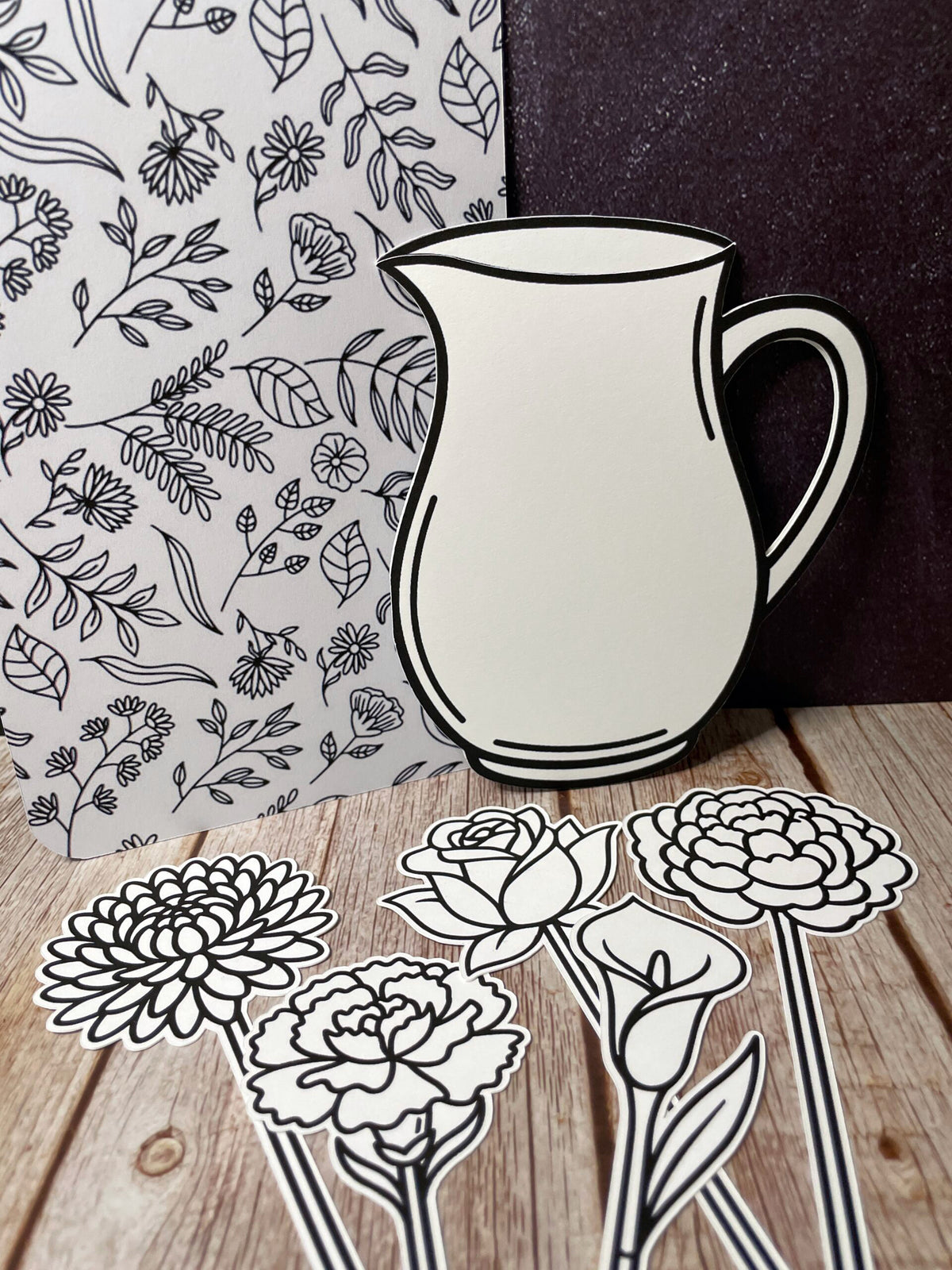 The five Flower Bundle cutouts laid out on wood, the pitcher standing in front of the art board with a chrysanthemum, carnation, rose, calla lily and peony arranged below it.