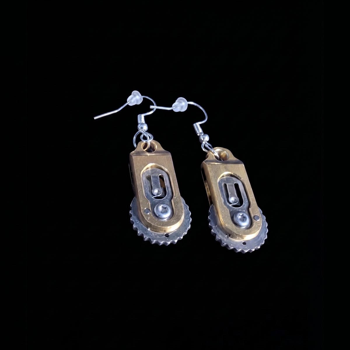 Gear pocket knife earrings by Pocket & Bear Collective closed on a black background, showing the brass handles with their gear-toothed edge and slotted gear detail