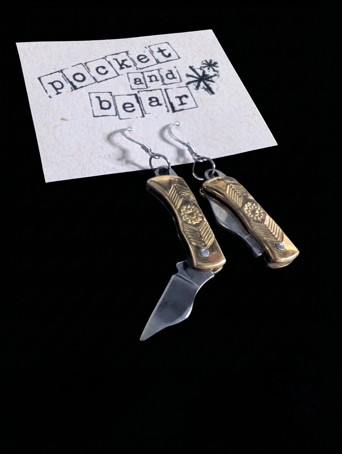 Brass flower mini pocket knife earrings by Pocket & Bear Collective on a stamped Pocket and Bear card with one blade open and one closed, shown close up