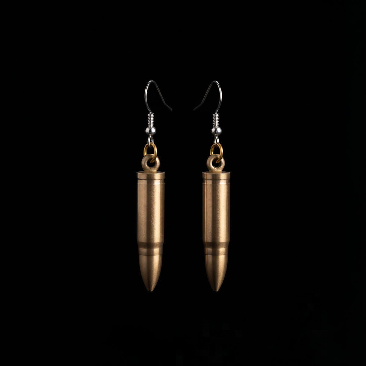 Bullet mini knife earrings by Pocket & Bear Collective, blades closed, shown on their own against a black background with the brass shells and stainless steel earring hooks in full view