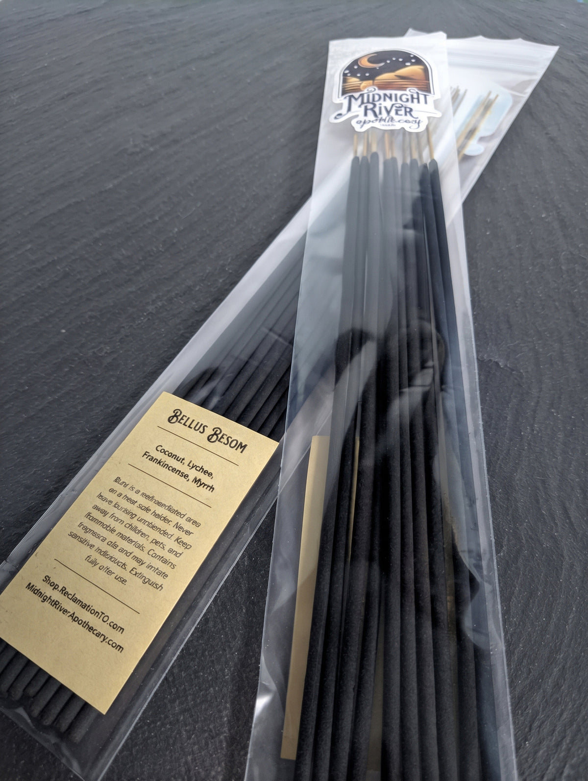 Bag of black Bellus Besom incense sticks from Midnight River Apothecary on a dark surface, angled to show the label and the sticks.