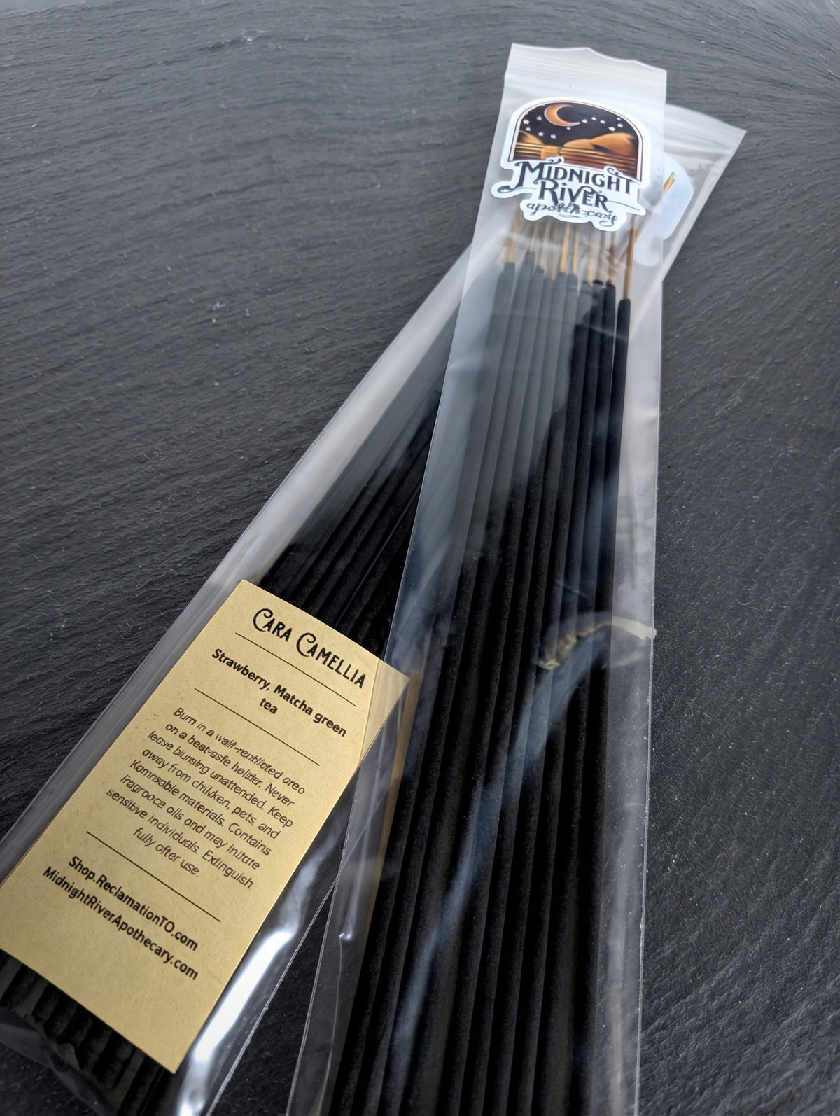 Second angled view of the bagged incense on dark slate, showing the label and the tops of the sticks