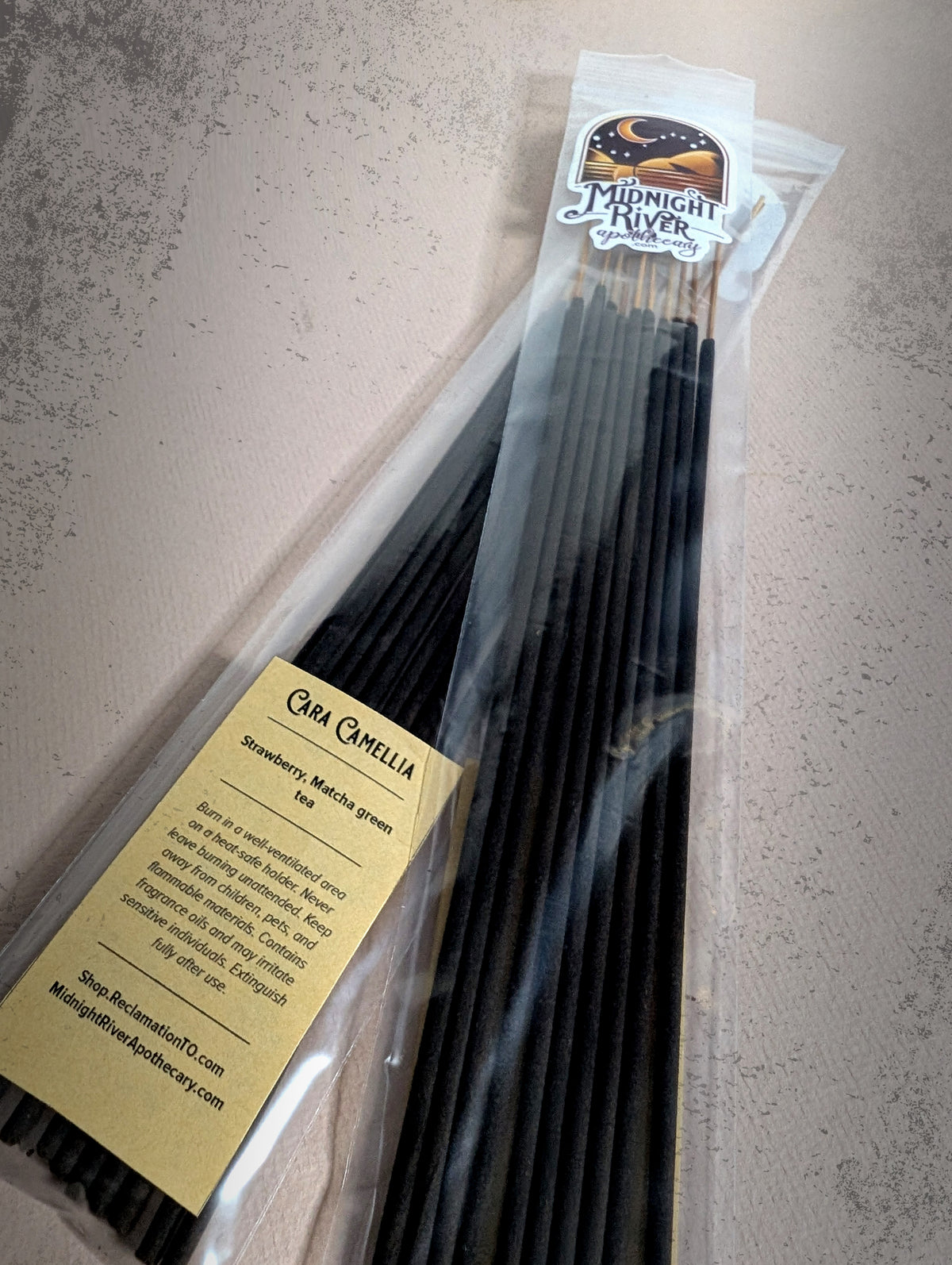 Third angled view of the bagged black incense bundle on dark slate, with the label near the bottom