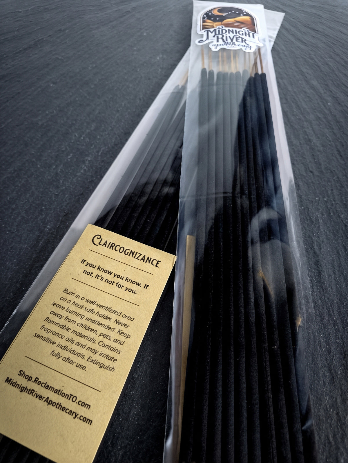 Bag of black Claircognizance incense sticks from Midnight River Apothecary on a dark surface, angled to show the label and the sticks.