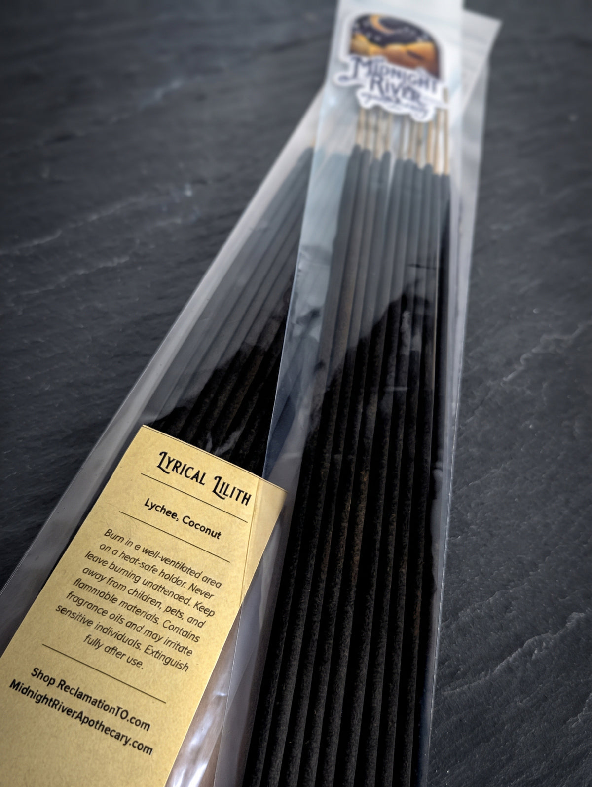 Bag of black Lyrical Lilith incense sticks from Midnight River Apothecary on a dark surface, angled to show the label and the sticks.