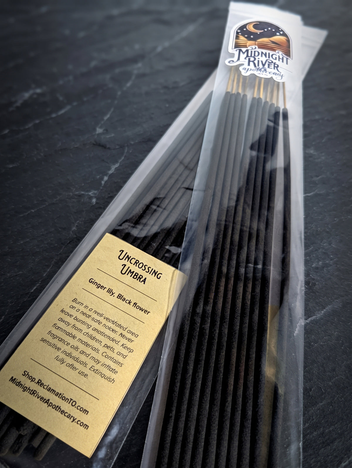 Bag of black Uncrossing Umbra incense sticks from Midnight River Apothecary on a dark surface, angled to show the label and the sticks.