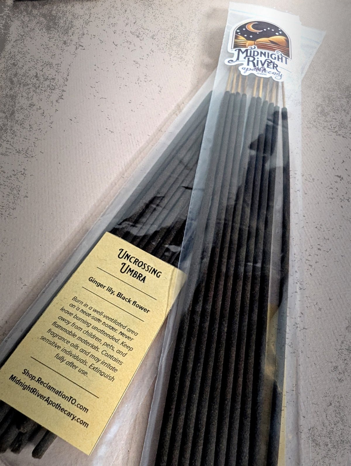 Second angle of the Uncrossing Umbra incense bag from Midnight River Apothecary, with the yellow label and the black sticks inside.