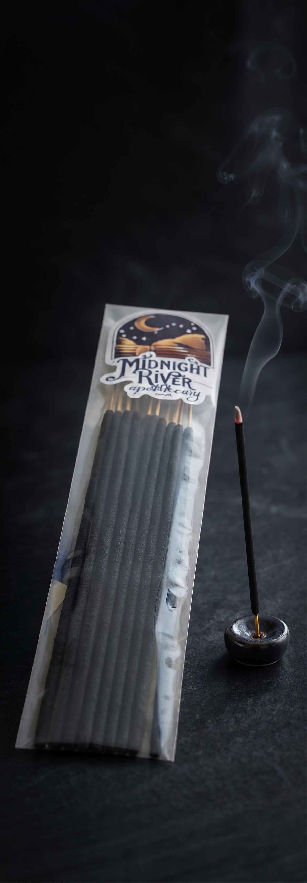 Tall narrow view of the bagged incense bundle beside a small incense holder, set against a dark background