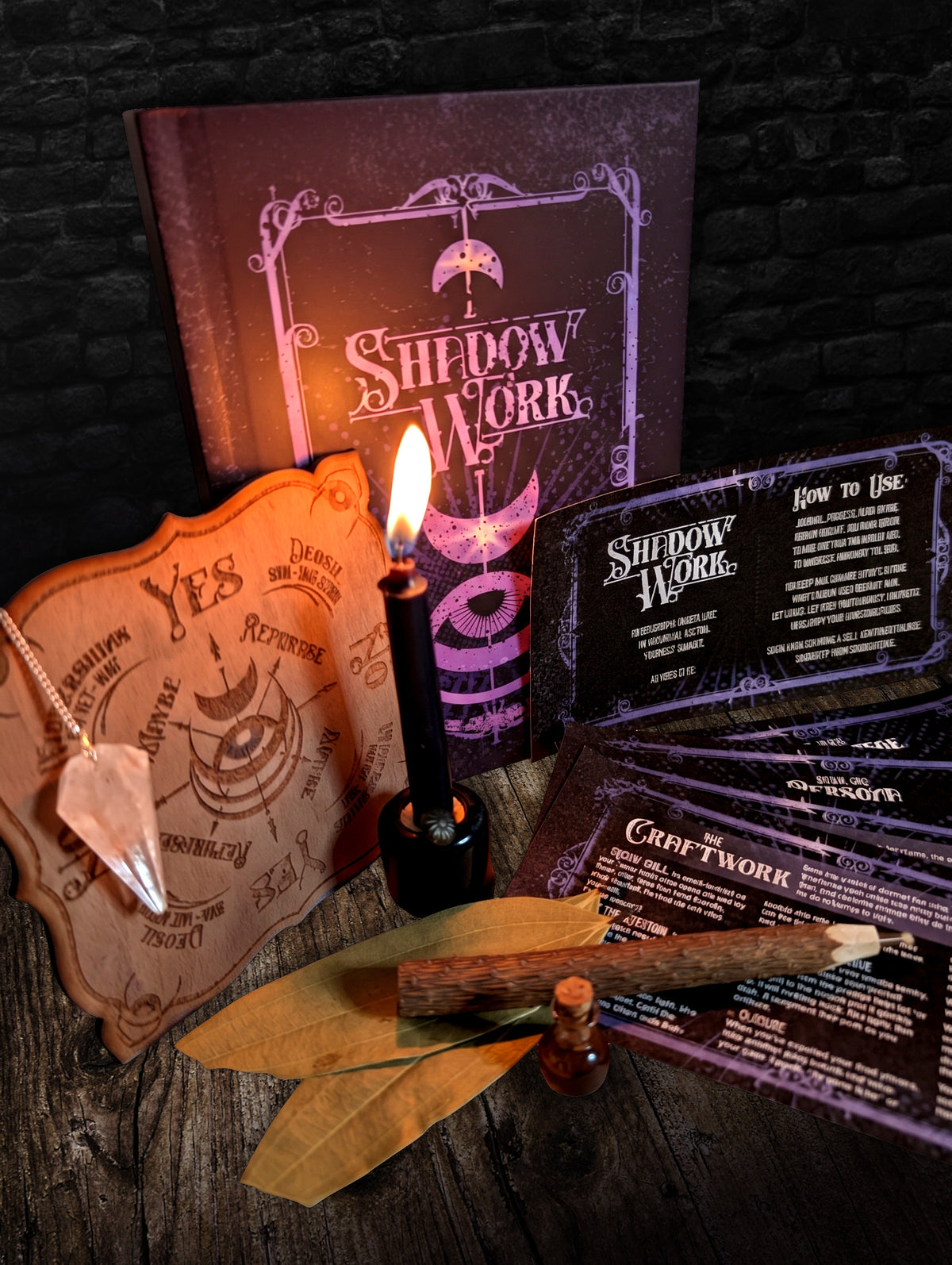 The Shadow Work Ritual Kit by candlelight, with the journal, the etched pendulum board and the cards spread on weathered wood