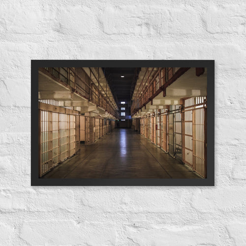 Alcatraz, San Francisco framed luster print by iain, black framed photograph of a long prison corridor lined with cells under warm lights, hanging on a white brick wall