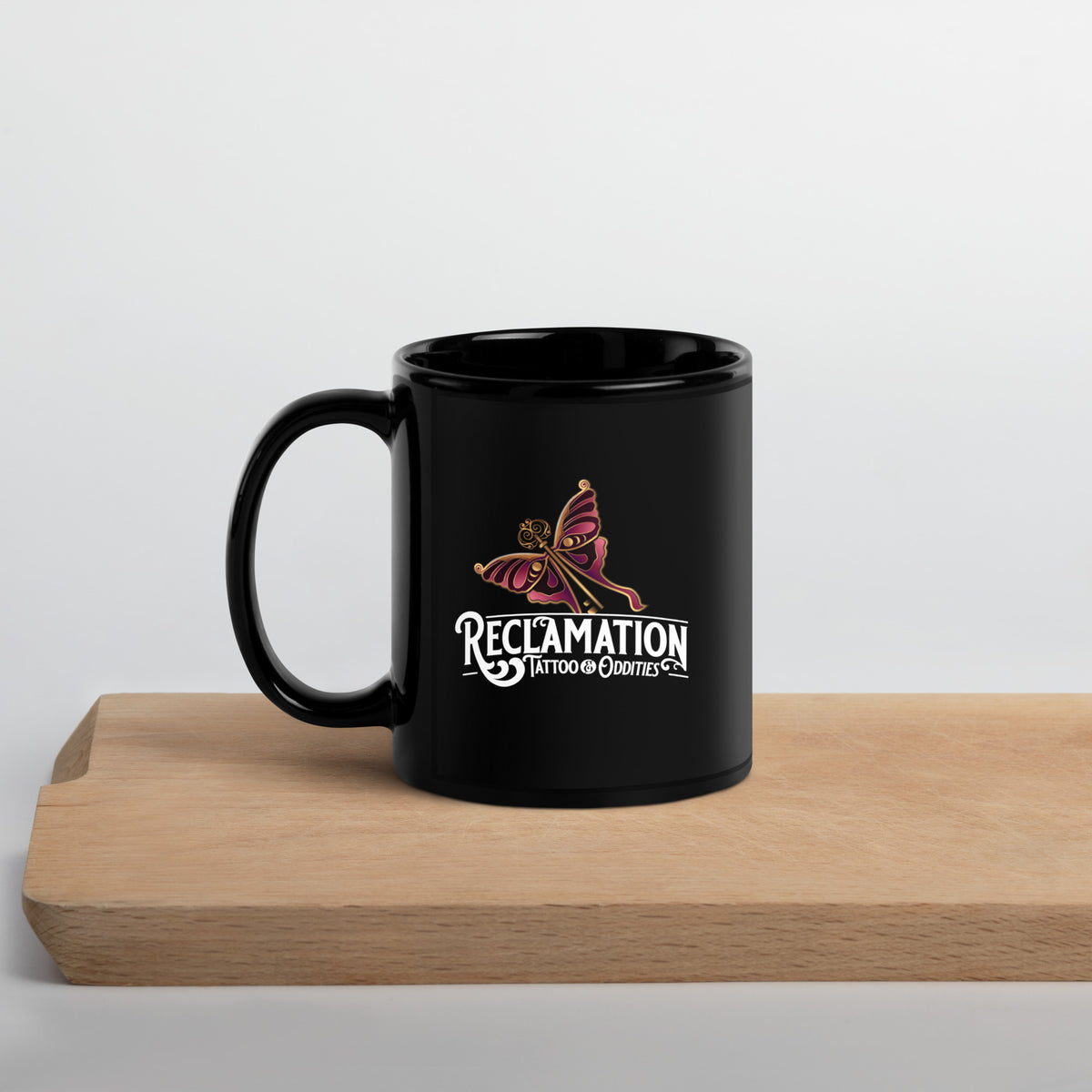 Reclamation & Midnight River mug, angled with the handle on the left, the Reclamation Tattoo & Oddities logo facing the camera