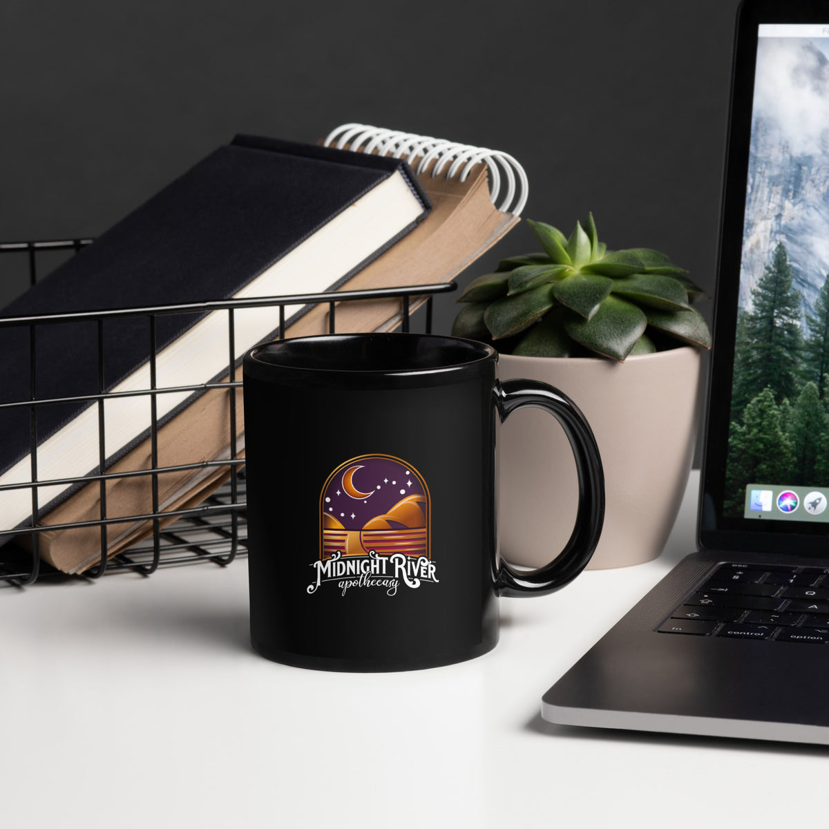 Reclamation & Midnight River mug, handle on the right, close view of the Midnight River Apothecary badge on the black glossy ceramic