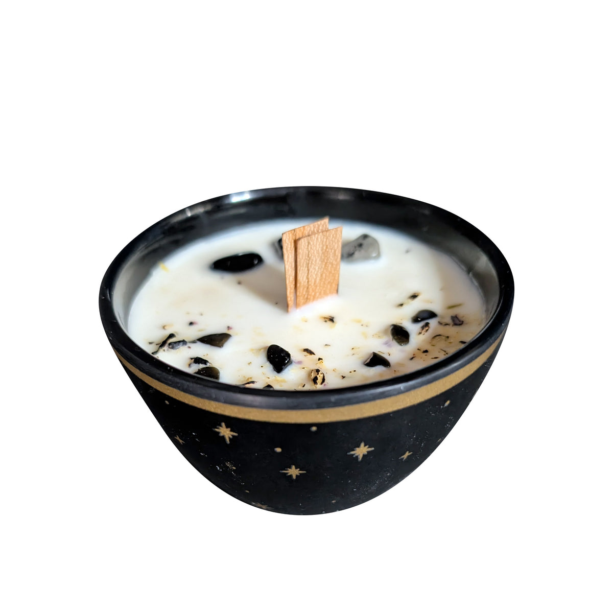 Black bowl candle with gold stars painted on the outside, seen from the front on a white background, cream soy wax set with black and snowflake obsidian around a wooden wick