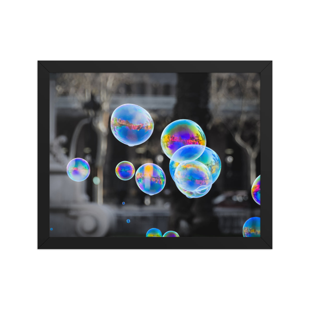 Bubbles of Barcelona framed luster print by iain, front view of the black framed print showing the colorful bubbles against the gray city behind them