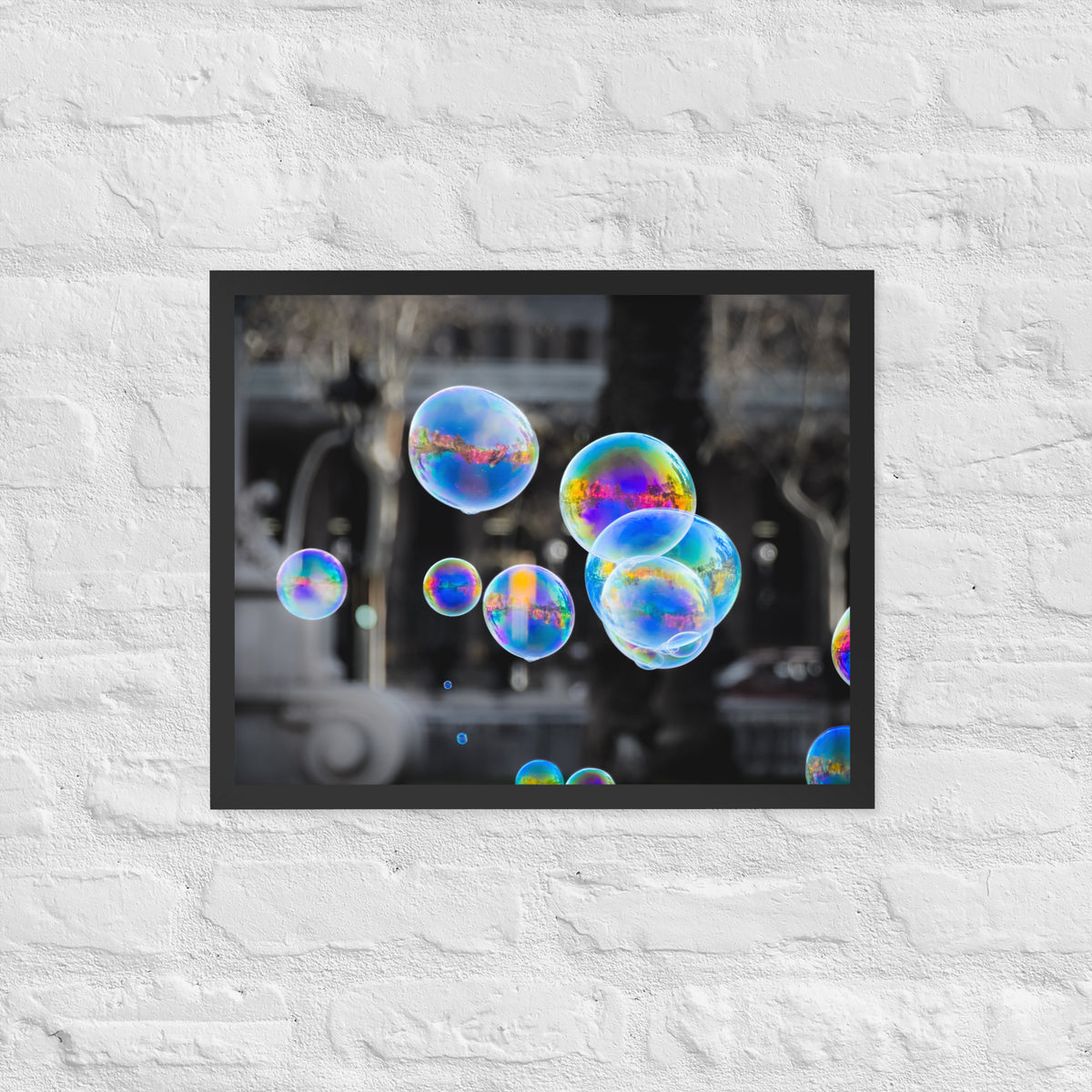 Bubbles of Barcelona framed luster print by iain, smaller black framed print hanging on a white brick wall