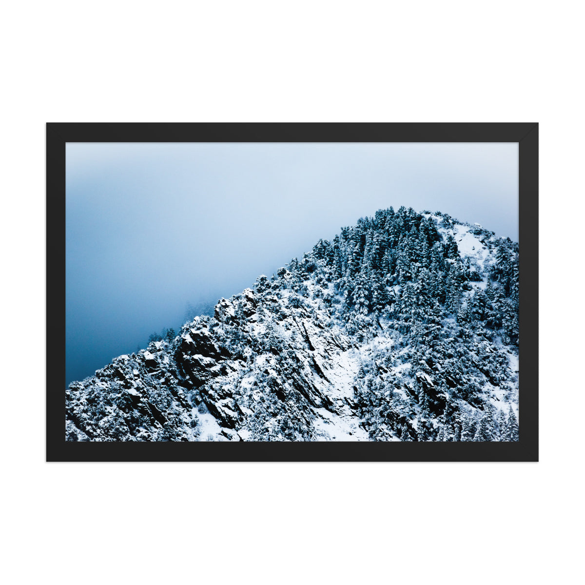 Colorado Mountain framed luster print by iain, front view of a black framed photograph of a snow covered mountain ridge with dense pine trees rising into cold blue cloud