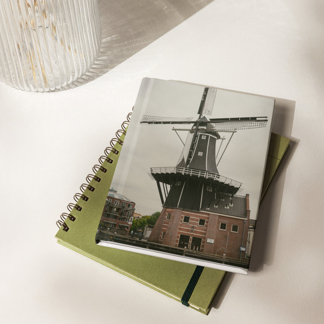 De Adriaan Windmill hardcover journal by iain, journal laying on green notebook on a table near a vase