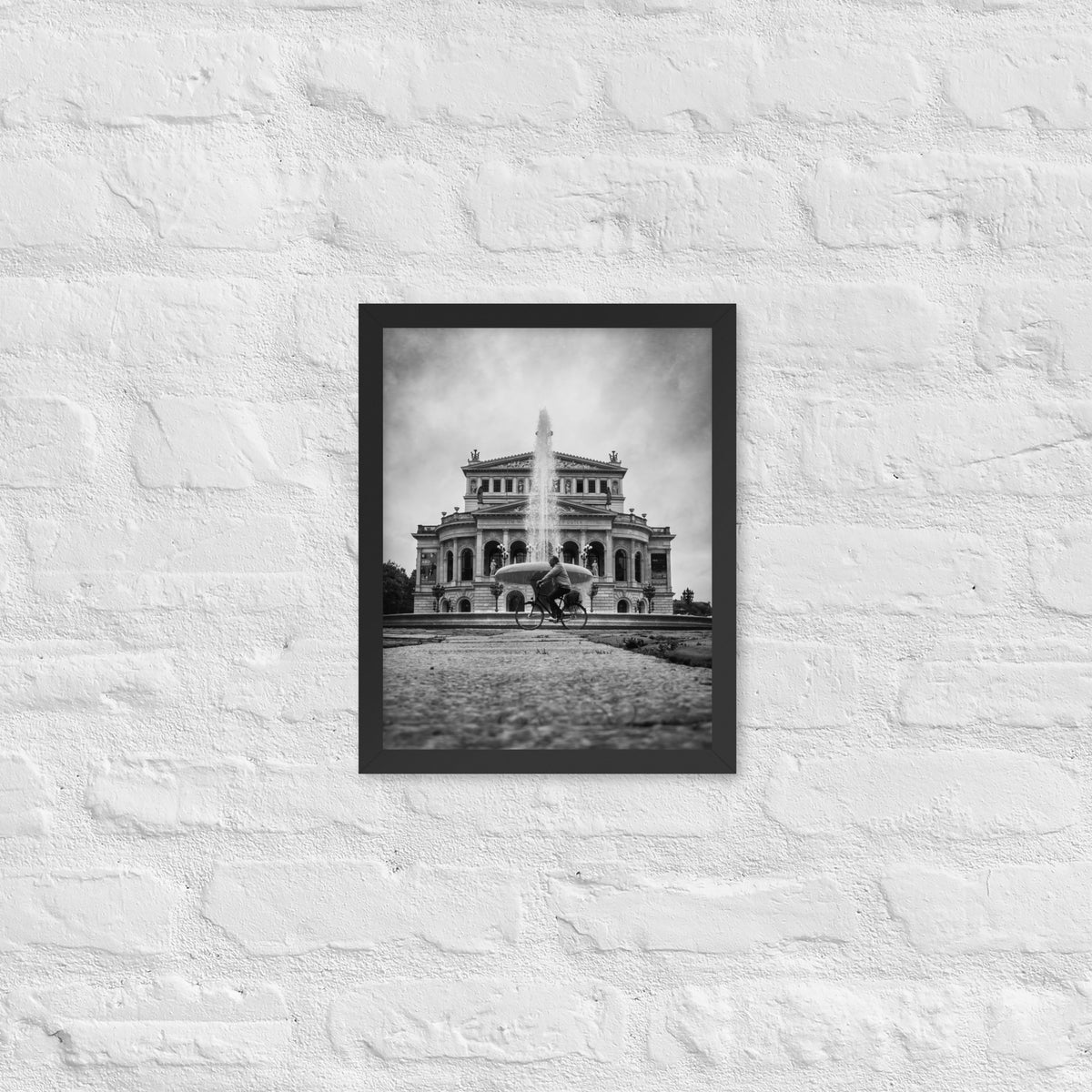 German Precision framed luster print by iain, smaller black framed print hanging on a white brick wall