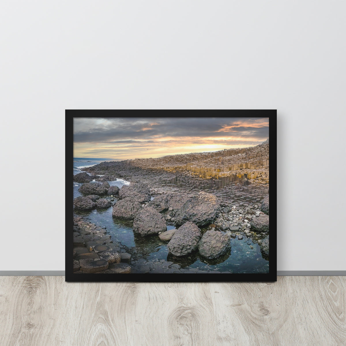Giant's Causeway, Northern Ireland framed luster print by iain, larger black framed print resting on a light wood floor against a white wall