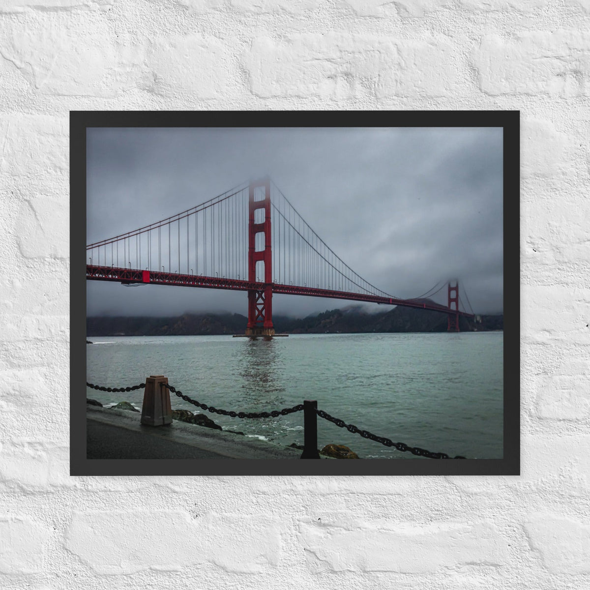 Golden Gate Bridge, San Francisco framed luster print by iain, black framed photograph of the red bridge fading into low fog over gray water, hanging on a white brick wall