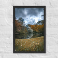 Hortus Botanicus, Amsterdam framed luster print by iain, black framed photograph of storm clouds over a pond and glasshouse surrounded by gold and orange autumn trees, hanging on a white brick wall