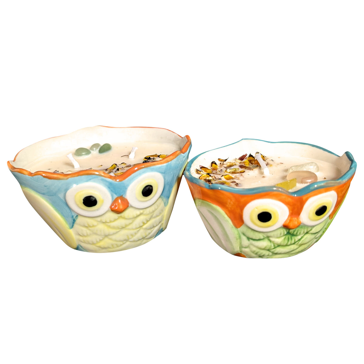 Pair of owl shaped ceramic candles standing side by side on a white background, soy wax poured level with the rim and topped with dried chrysanthemum petals and small stones