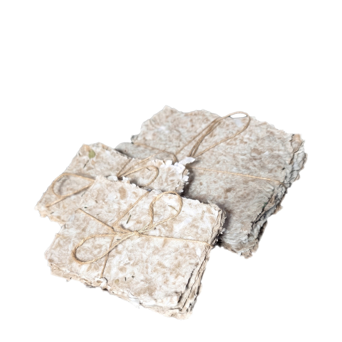 Bundles of handmade paper tied with twine seen from the side on a white background, showing the stacked sheet thickness and uneven edges