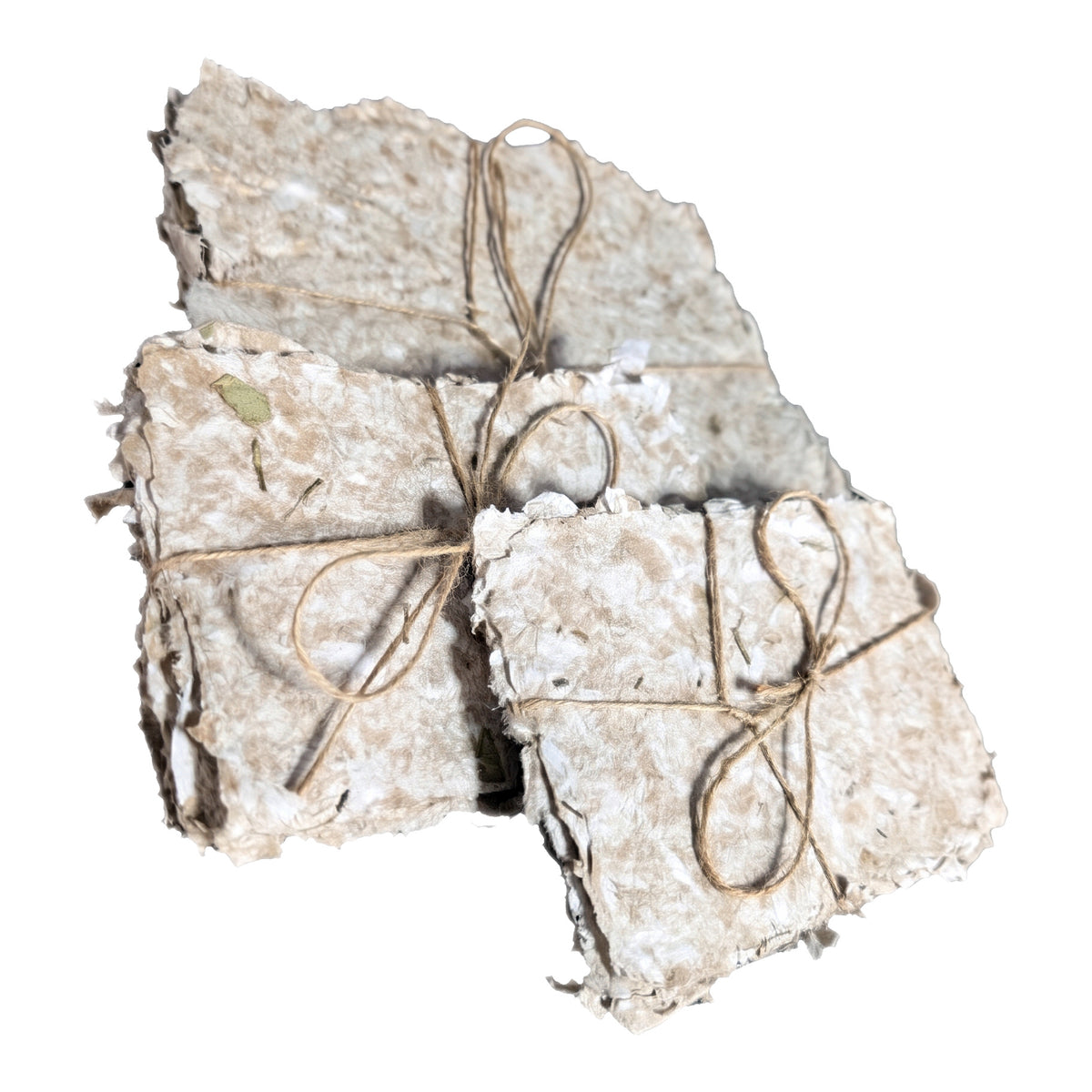 Three bundles of handmade paper tied with twine on a white background, one standing upright behind the others, cream pulp with deckle edges and flecks of dried herbs