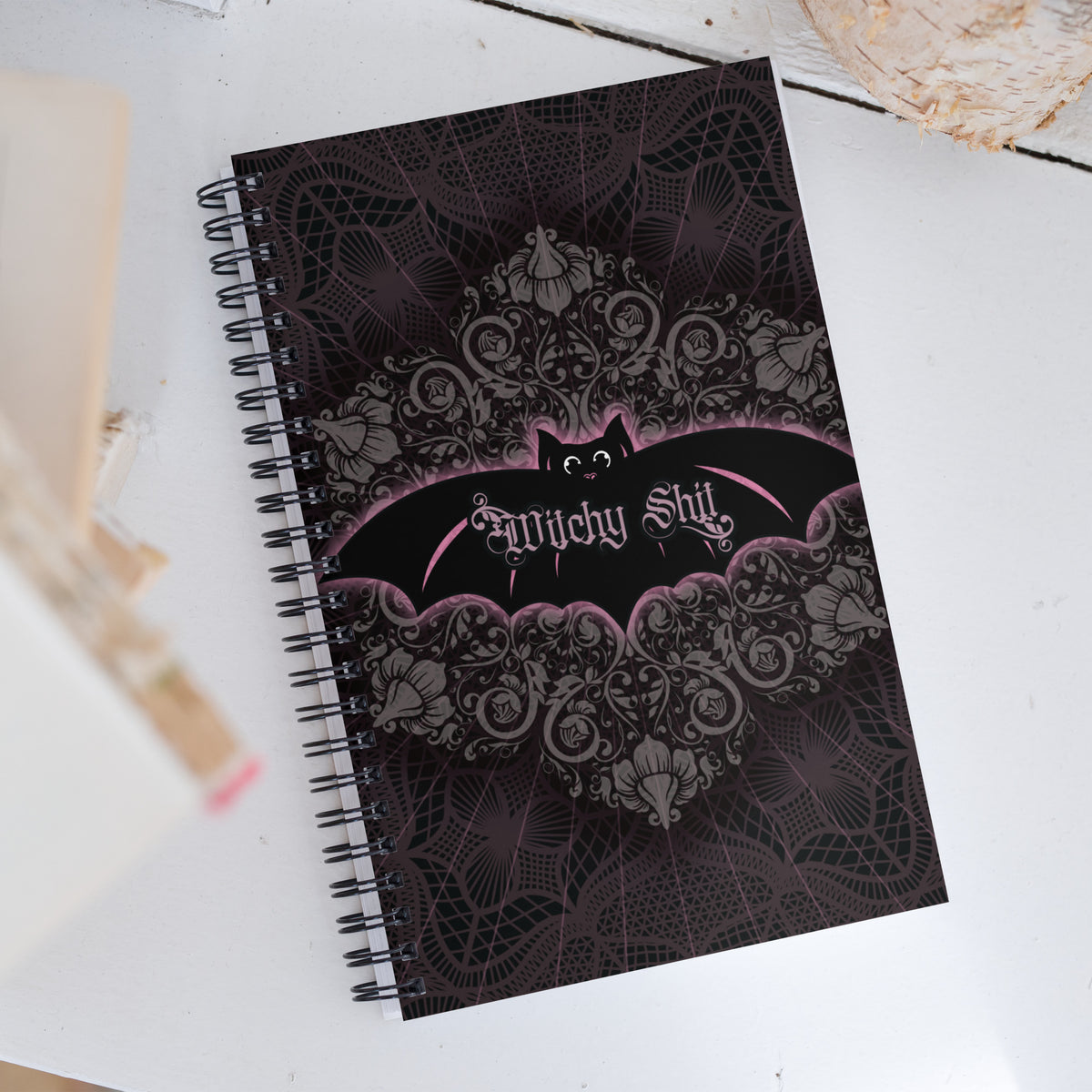 Witchy Shit spiral notebook lying flat at an angle, showing the full bat and lace cover design