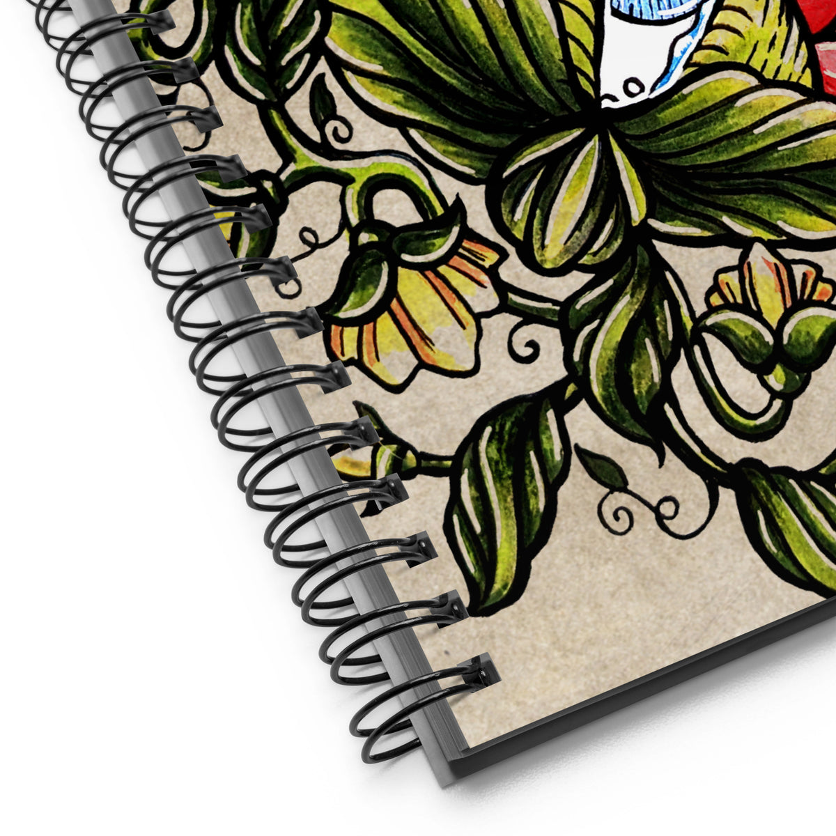Close up of the notebook's black wire binding and the corner of the cover art, showing the leaf and flower line work in detail