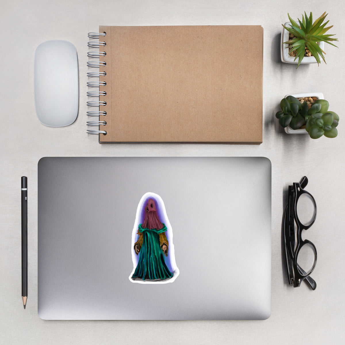 Matte vinyl sticker applied to the lid of a silver laptop on a desk setup with office accessories.