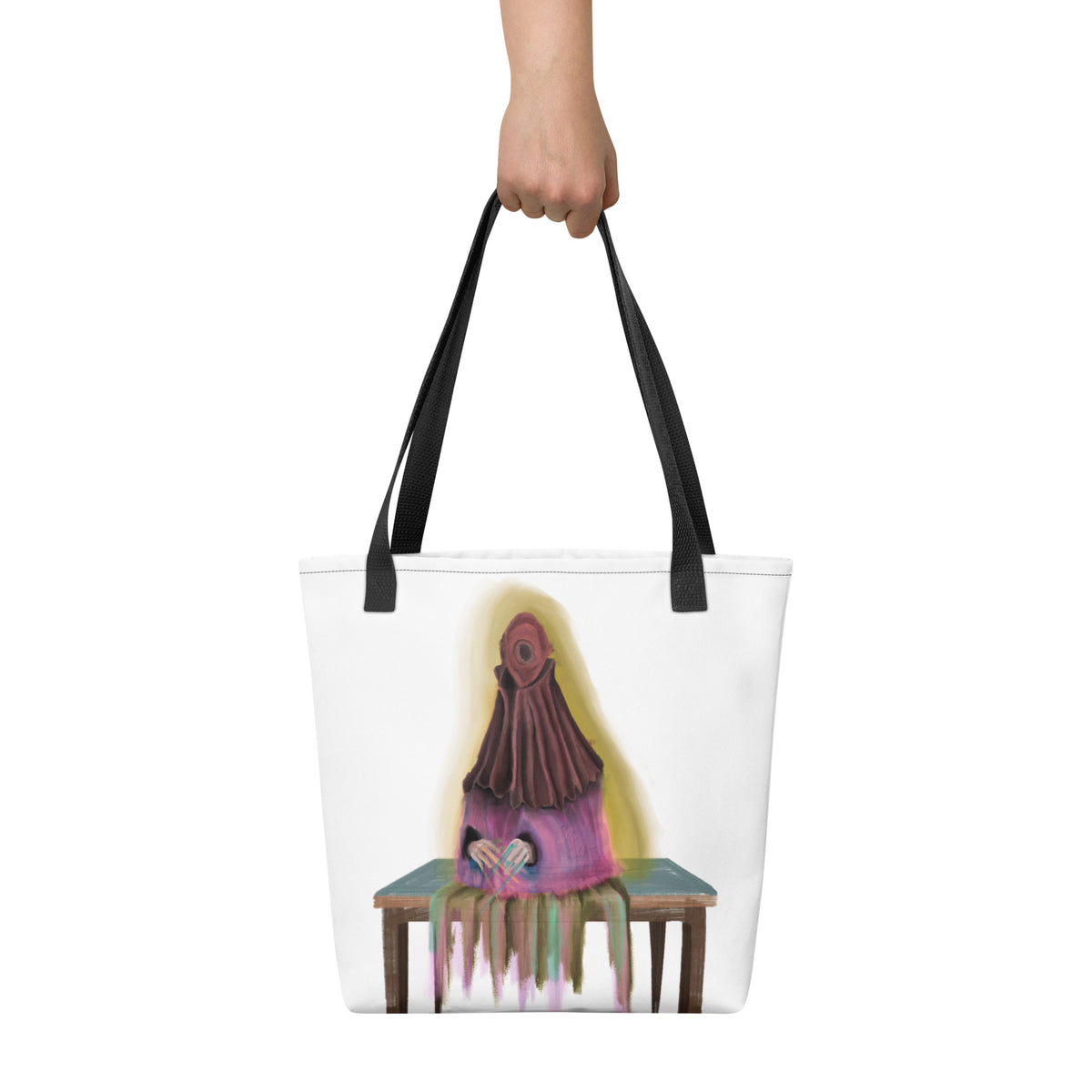 White tote bag held up by a hand against a neutral background, displaying the scale and vertical placement of the front graphic.