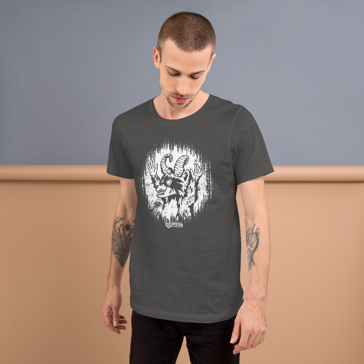 Model wearing the Cornelius Baphomet t-shirt in asphalt grey, looking down, with the horned raccoon printed across the chest