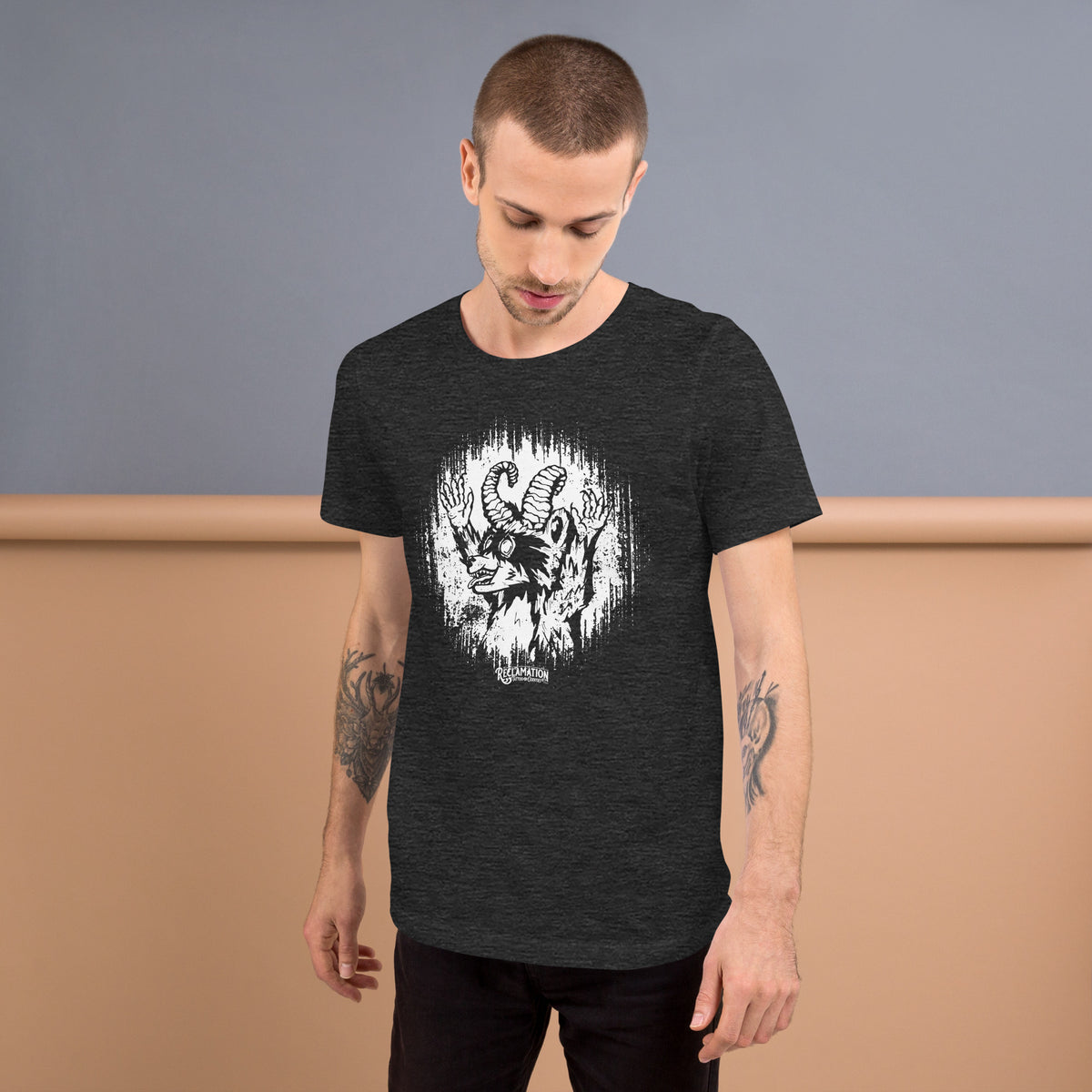 Model wearing the Cornelius Baphomet t-shirt in dark grey heather, turned slightly to the side, with the horned raccoon printed across the chest